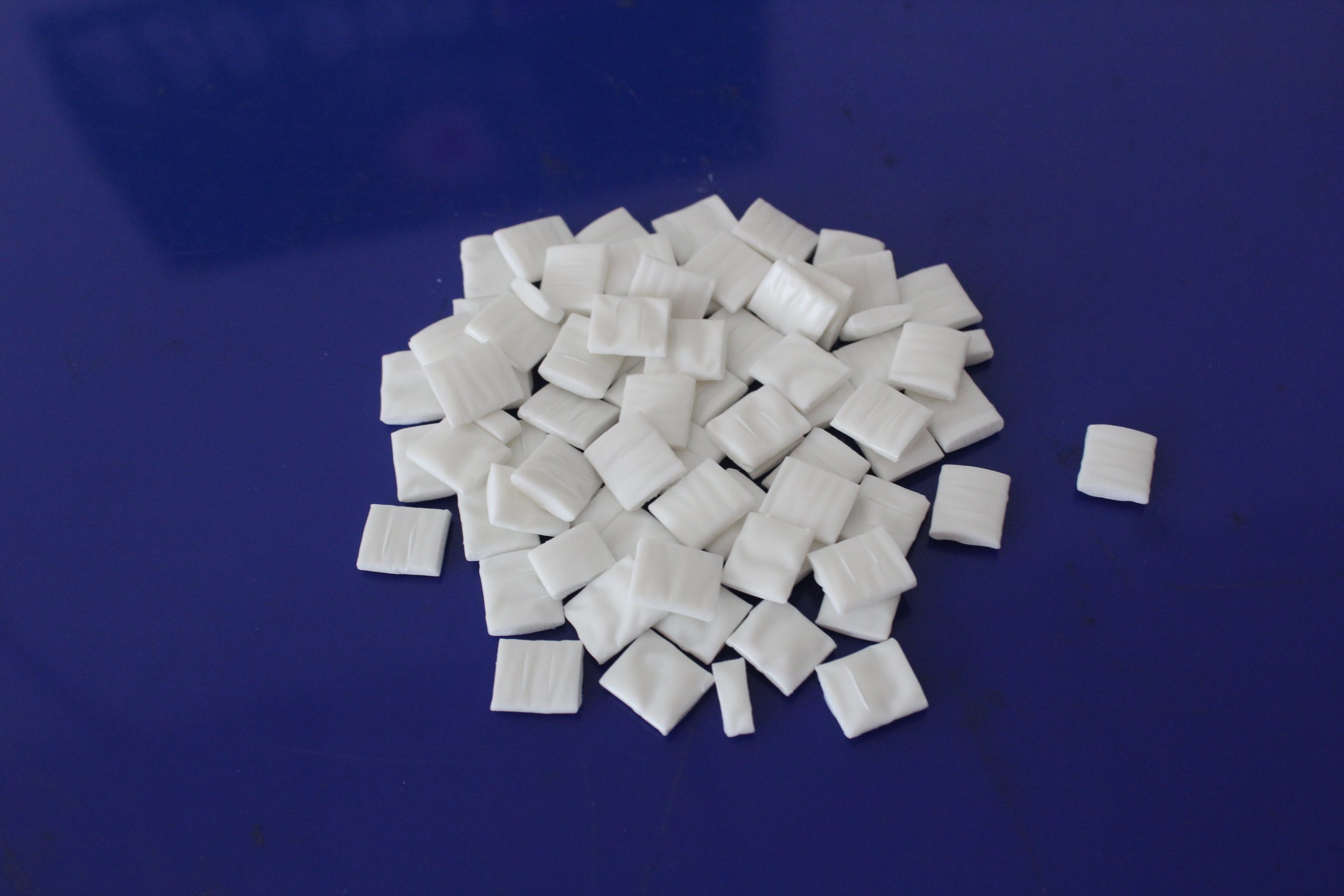 What are the factors that affect the poor flowability of hot melt adhesive particles?